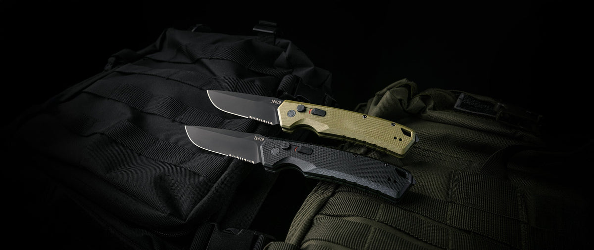 Two TEKTO A3 Delta automatic knives on dark fabric