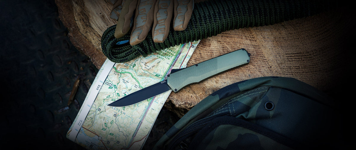 TEKTO A5 Spry OTF knife resting on a map with a backpack behind it